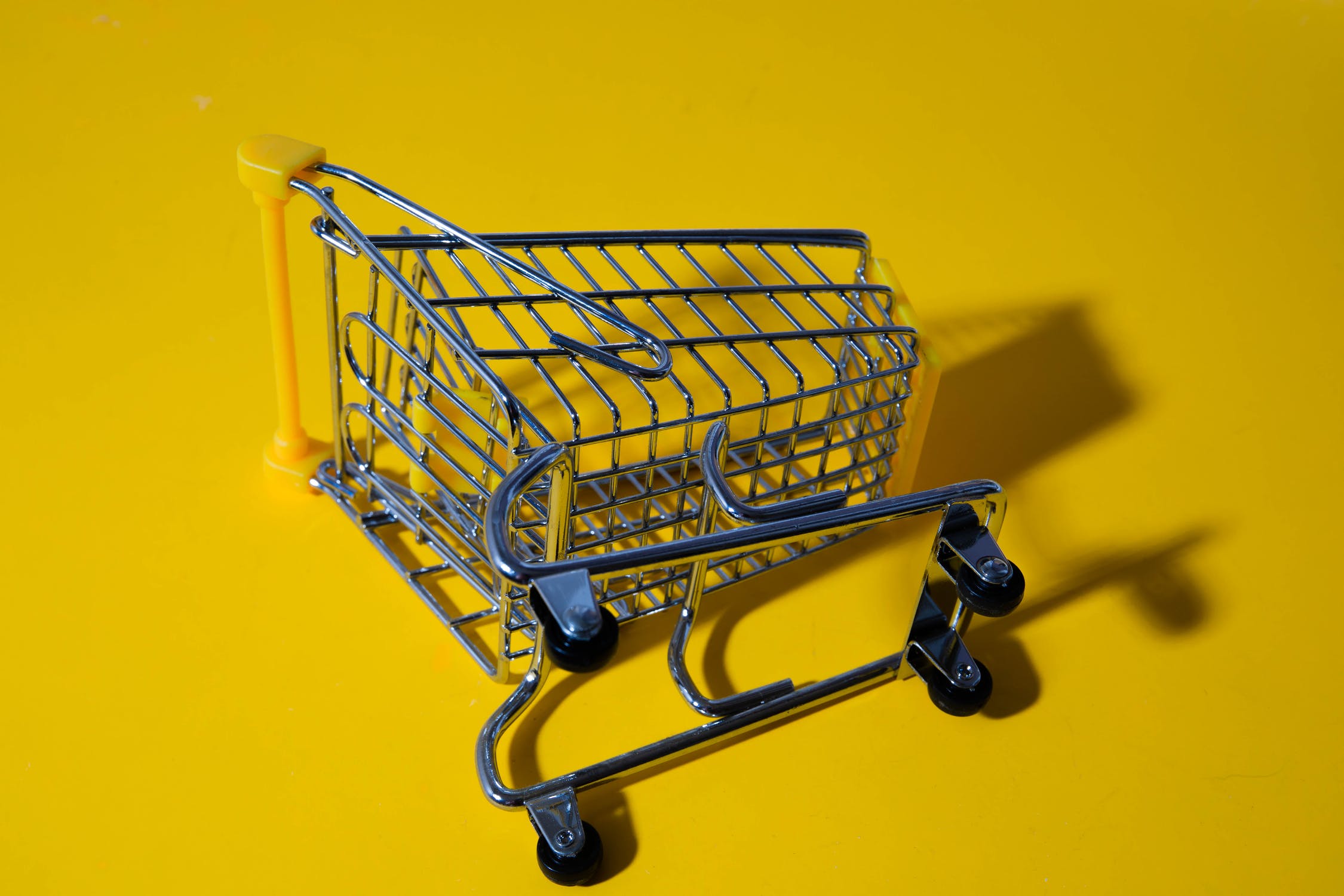 A toy shopping cart on its side on a yellow surface