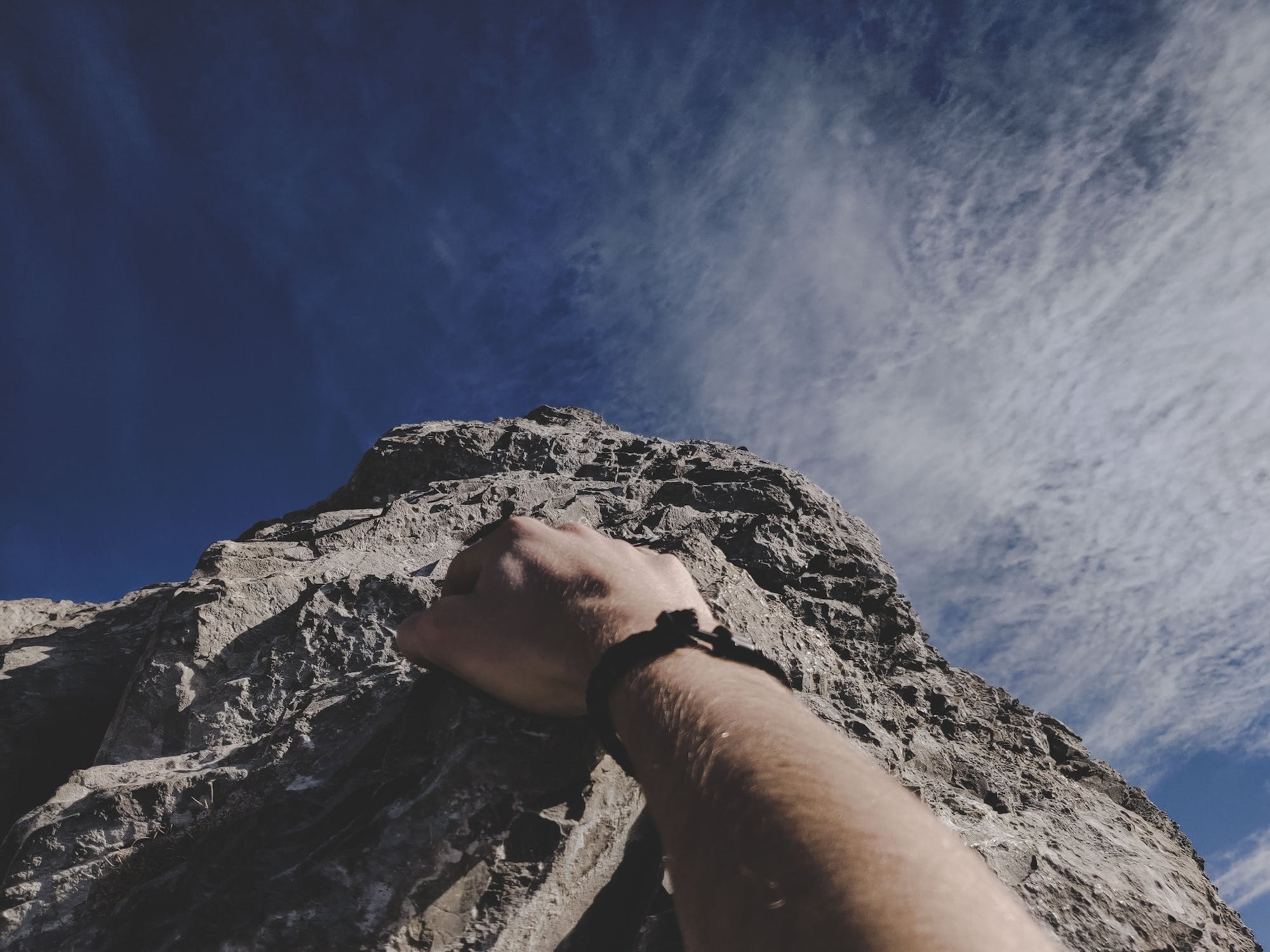 A person’s hand as they’re climbing a mountain.