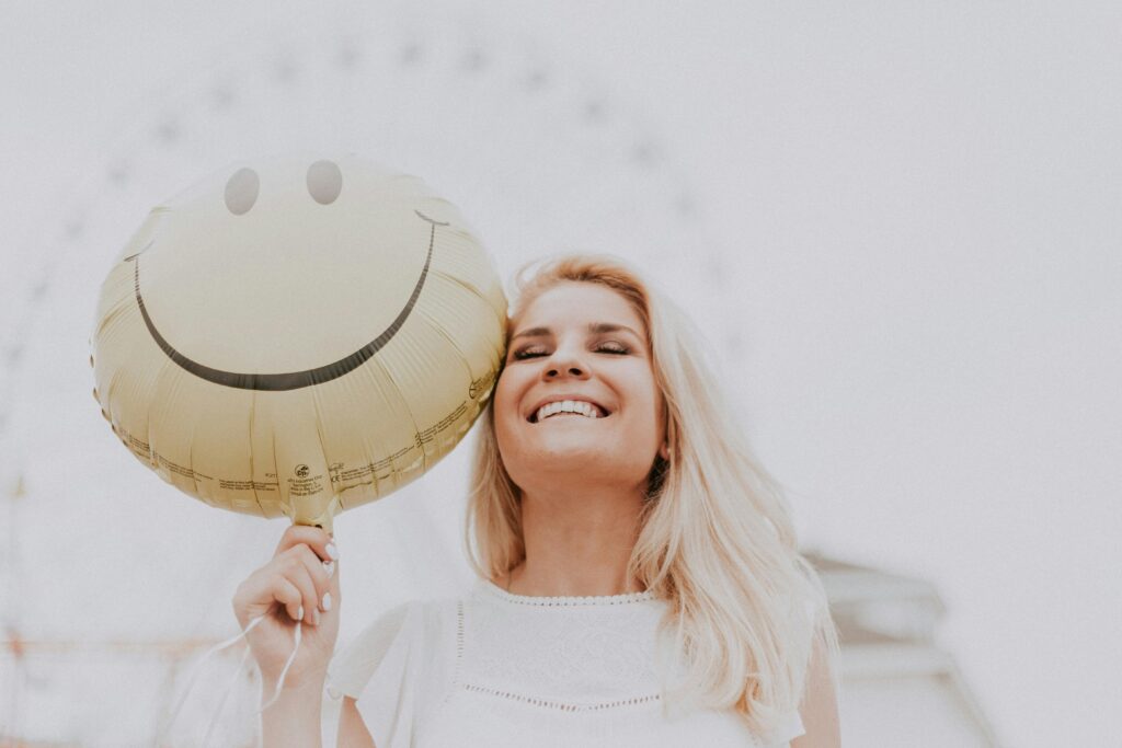 a woman holding a big smiley balloon