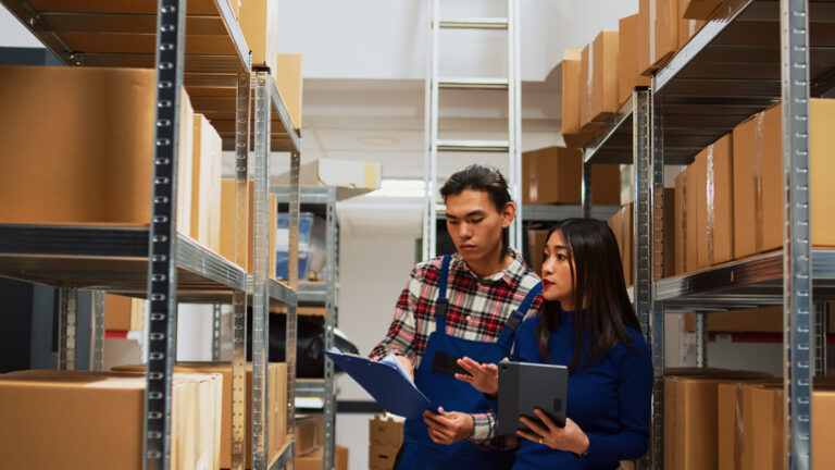 Asian employees checking warehouse supplies on tablet